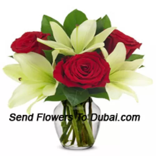 Roses rouges et lys blancs avec des remplisseurs saisonniers dans un vase en verre