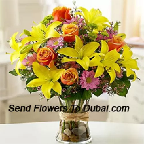 Lys jaunes, roses oranges et gerberas roses avec des remplisseurs saisonniers dans un vase en verre