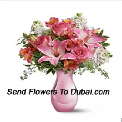 Roses roses, lys roses et diverses fleurs blanches avec quelques fougères dans un vase en verre